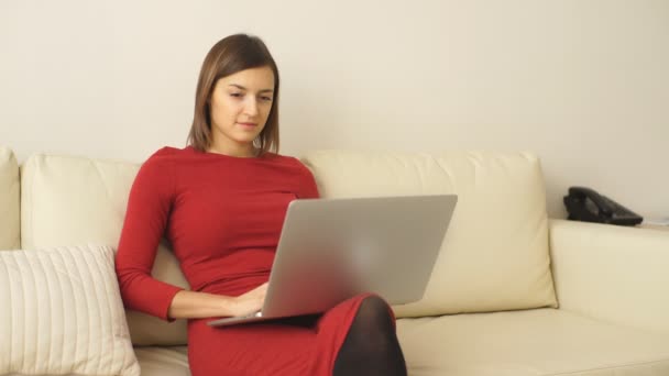 Hermosa mujer joven utiliza un ordenador portátil en una habitación de hotel — Vídeos de Stock