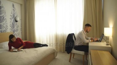 otel odası, bilgisayar, yatakta dergi okuma kız adama