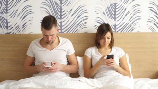 Couple heureux en utilisant les réseaux sociaux avec leurs téléphones dans le lit — Video