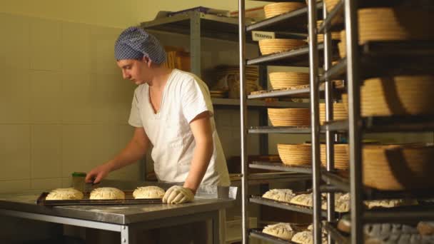 Un panadero hace incisiones manuales en la masa para el pan. La fabricación de panadería.Panadería — Vídeos de Stock