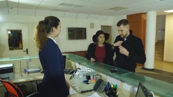 Érkezéskor a hotel recepcióján fiatal pár. — Stock videók