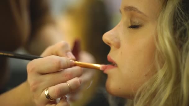 Visagistin trägt Lippenstift mit Pinsel auf Models Lippen auf — Stockvideo