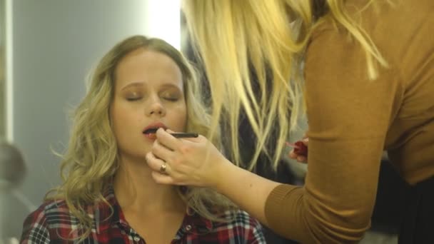 Artista de maquilagem que aplica batom com uma escova em lábios de modelos — Vídeo de Stock