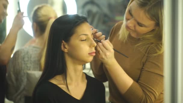 Maquiagem artista criando maquiagem bonita para brunettemodel — Vídeo de Stock