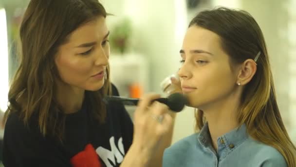 Jonge mooie vrouw aanbrengen van make-up door make-up kunstenaar — Stockvideo