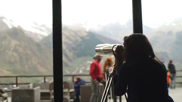 Молода жінка дивиться через телескоп у горах — стокове відео