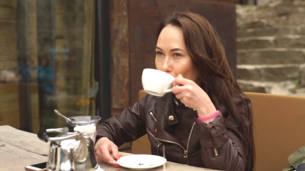 Jonge mooie vrouw, drinken koffie in het café op de straat — Stockvideo