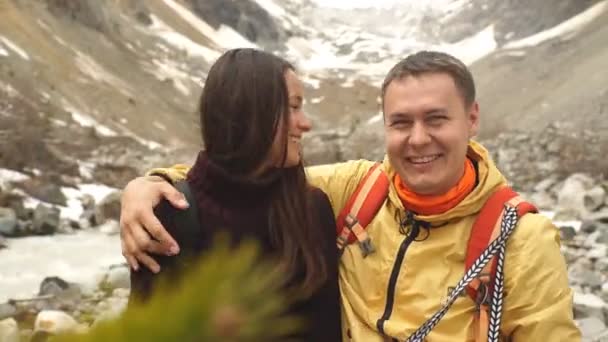 Beautiful couple sitting on the stone in the mountains and admire the scenery — Stock Video