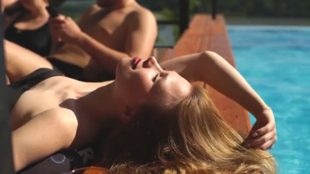 Jonge vrouw zonnebaden bij het zwembad — Stockvideo