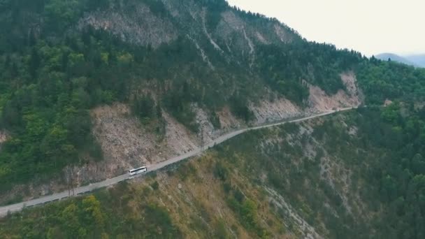 Автобус, путешествующий по горной дороге, снятый с воздуха — стоковое видео