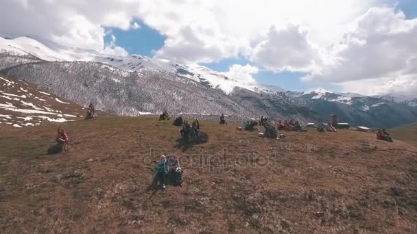 En grupp turister sitter på ett berg och tittar på glaciären — Stockvideo