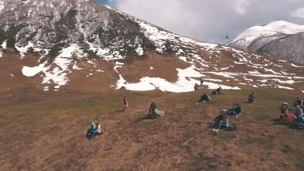 Eine Gruppe Touristen sitzt auf einem Berg und blickt auf den Gletscher — Stockvideo