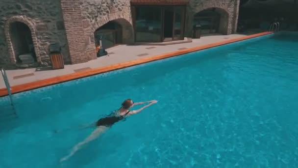 Una mujer joven nada en la piscina — Vídeo de stock