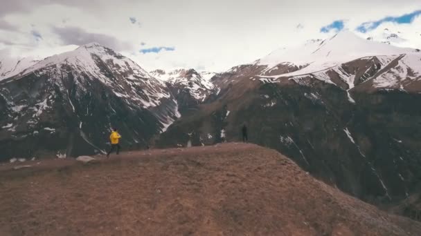 Ein Mann nimmt eine Frau am Rande eines Berges auf — Stockvideo
