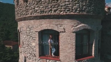 Kalenin penceresinden sallayarak güzel genç kadın