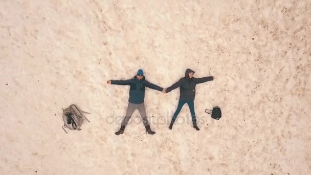 Paar liegt im Schnee, schießt mit der Drohne, Luftaufnahme — Stockvideo