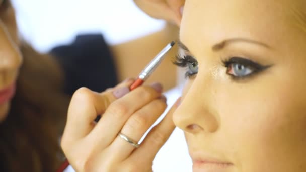 Joven hermosa mujer aplicando maquillaje por maquillador — Vídeos de Stock