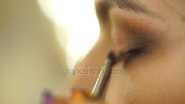 Maquillaje artista aplicando sombra de ojos de color base brillante en los modelos de ojo y sosteniendo una cáscara con sombra de ojos — Vídeos de Stock