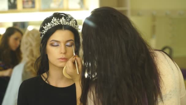 Joven hermosa mujer aplicando maquillaje por maquillador — Vídeos de Stock