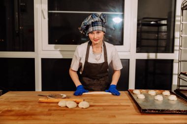 Kadın fırında pasta. Şekerlemeciler tatlılar olun. Çörekler yapma. Hamur masada