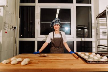 Kadın fırında pasta. Şekerlemeciler tatlılar olun. Çörekler yapma. Hamur masada