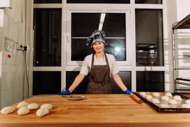 Kadın fırında pasta. Şekerlemeciler tatlılar olun. Çörekler yapma. Hamur masada