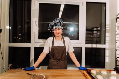 Kadın fırında pasta. Şekerlemeciler tatlılar olun. Çörekler yapma. Hamur masada