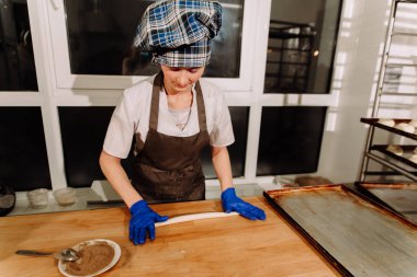 Kadın fırında pasta. Şekerlemeciler tatlılar olun. Çörekler yapma. Hamur masada