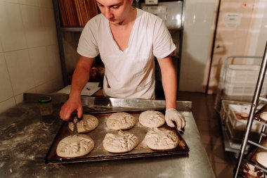 bir fırıncı ekmek hamur üzerinde el ile insizyon yapar. Bread.Bakery imalatı