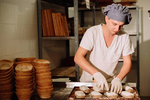 Un boulanger fait des incisions manuelles sur la pâte pour le pain. La fabrication du pain. Boulangerie — Photo