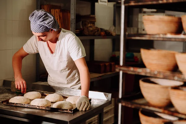 bir fırıncı ekmek hamur üzerinde el ile insizyon yapar. Bread.Bakery imalatı