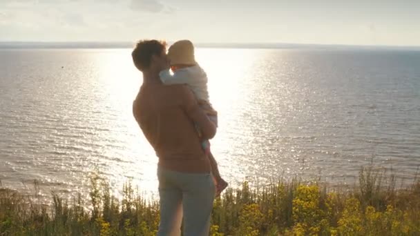 Pappa håller dotter på händerna på kanten av klippan — Stockvideo