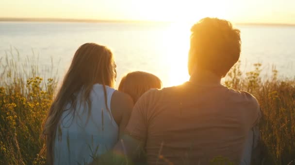 Kijken naar de zonsondergang op de achtergrond van de rivier en gelukkige familie — Stockvideo