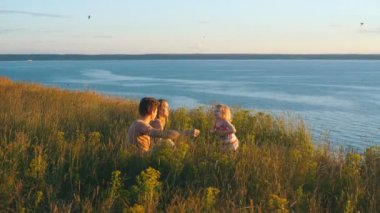 mutlu aile nehrin arka plan üzerinde gün batımını izlemek