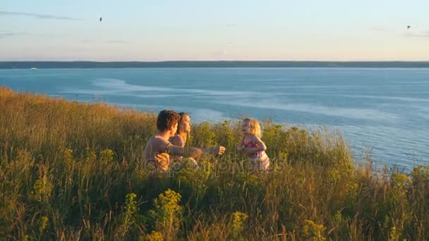 Famille heureuse regardant le coucher du soleil sur le fond de la rivière — Video