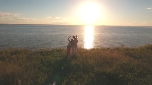 Heureux famille debout sur le bord de la falaise contre la mer et le coucher du soleil, tir de l'air — Video