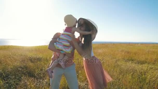 Щасливі батьки тримають свою дочку на руках і цілують — стокове відео