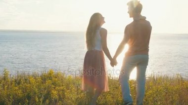 gün batımı ve deniz karşı uçurumun kenarına mutlu aile ayakta,