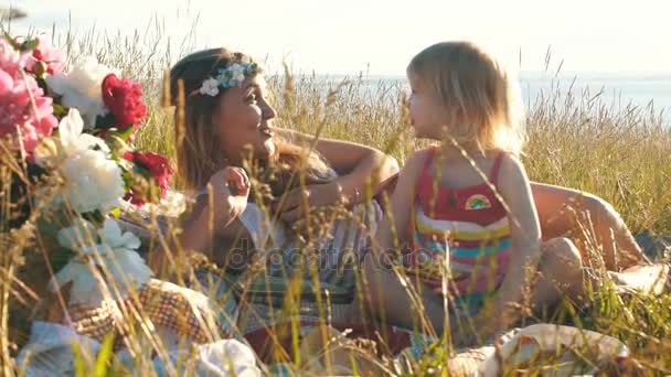 Feliz madre con hija pequeña sentarse en el campo y tontear — Vídeo de stock