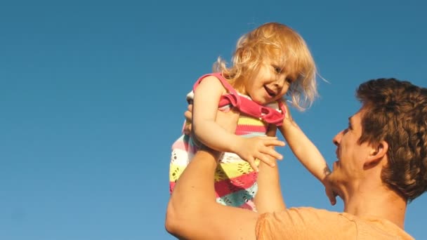 Батько кидає дитину в повітря на пляжі — стокове відео