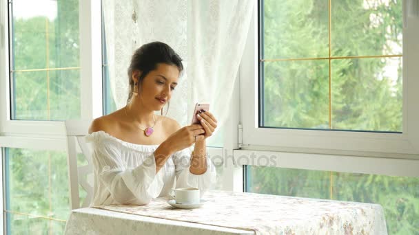 Mujer mensajes de texto en el teléfono inteligente en una terraza del restaurante — Vídeos de Stock