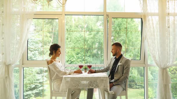 Cheerful couple in a restaurant with glasses of red wine — Stock Video