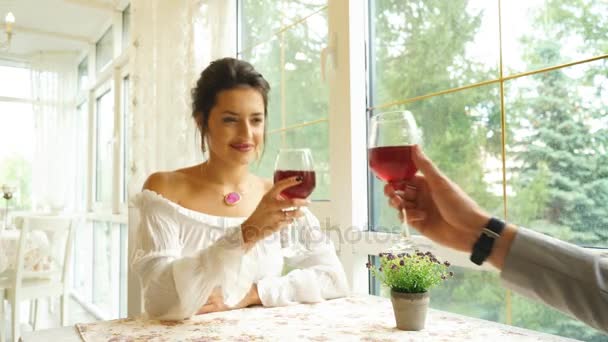 Hermosa pareja joven con copas de vino tinto en un restaurante de lujo — Vídeo de stock