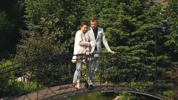 Jeune beau couple marchant dans le parc et se tient sur le pont — Video