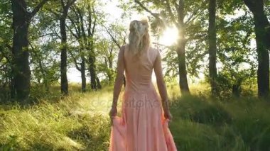 Şeftali renkli elbiseli güzel sarışın ormanda yürür ve iyi eğlenceler