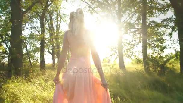 Hermosa rubia en un vestido de color melocotón paseos por el bosque y divertirse — Vídeo de stock