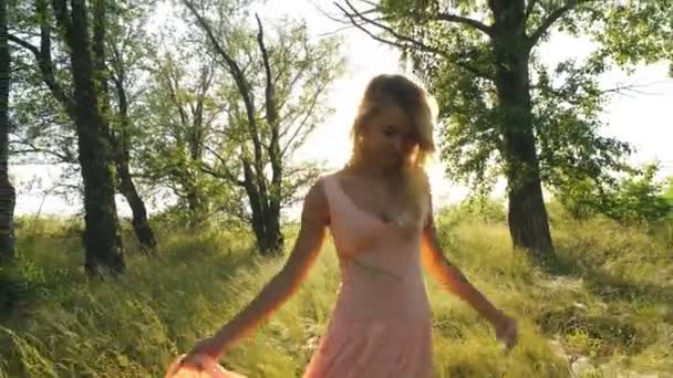Bela loira em um vestido de passeios cor de pêssego na floresta e se divertir — Vídeo de Stock