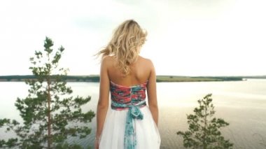 sarışın güzel bir elbise bu uçurumun kenarında duran ve nehirde seyir içinde