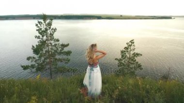 sarışın güzel bir elbise bu uçurumun kenarında duran ve nehirde seyir içinde