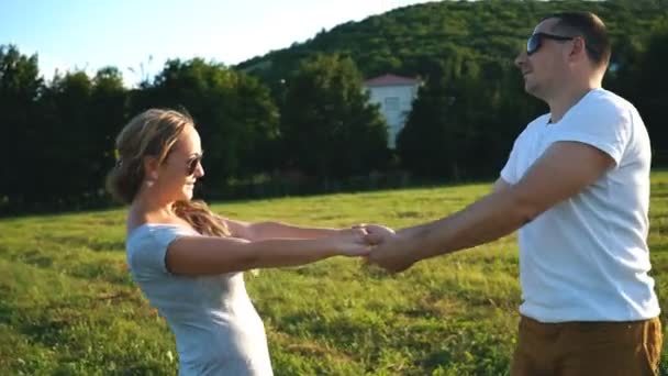 Привлекательная пара, держащаяся за руки и кружащаяся на лугу в свободное время — стоковое видео